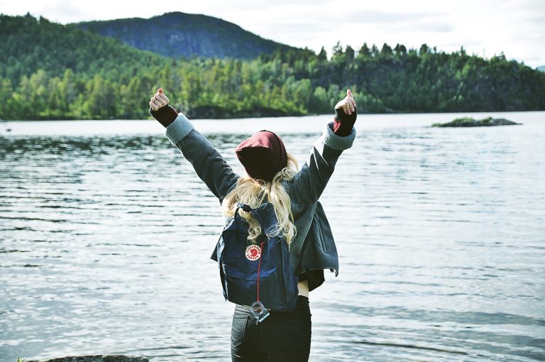 a person holding a dog in the air in front of a lake