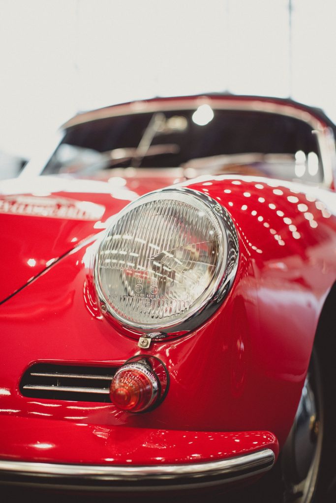 a red sports car with a silver plate and a white wall