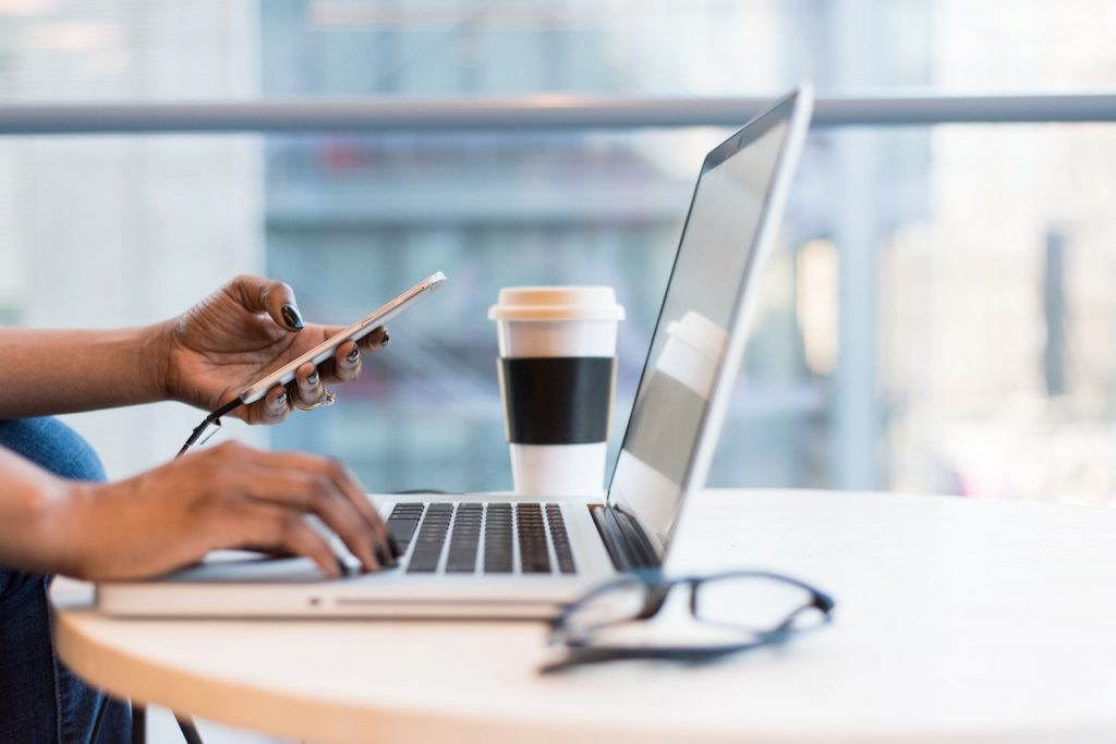 close-up of a hand holding a pen and a laptop