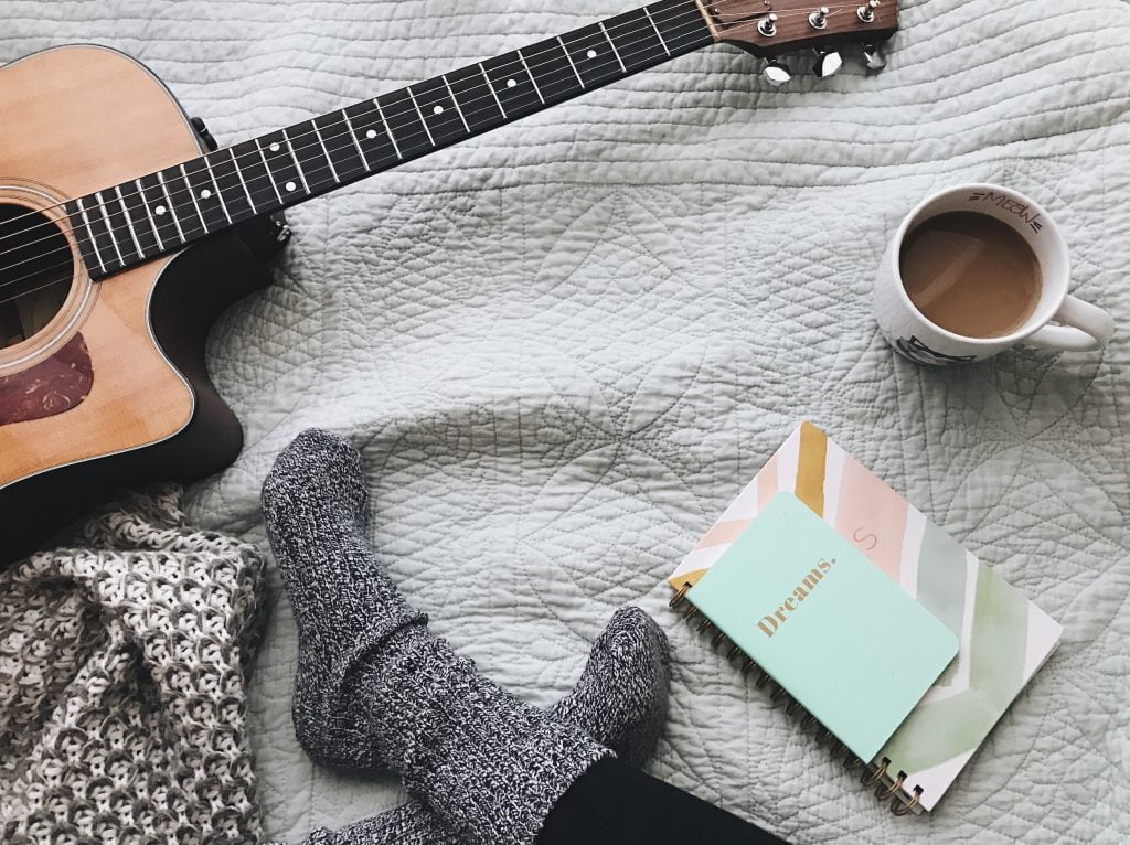 a person with a guitar and a blanket on a rug