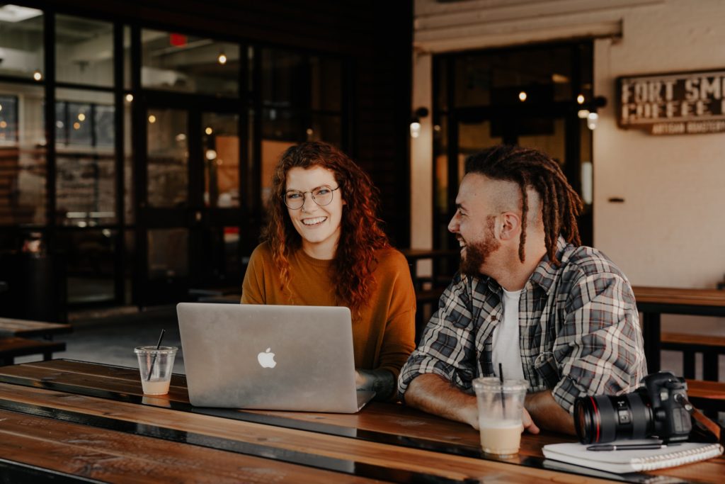 a man and a woman sitting at a table with a laptop