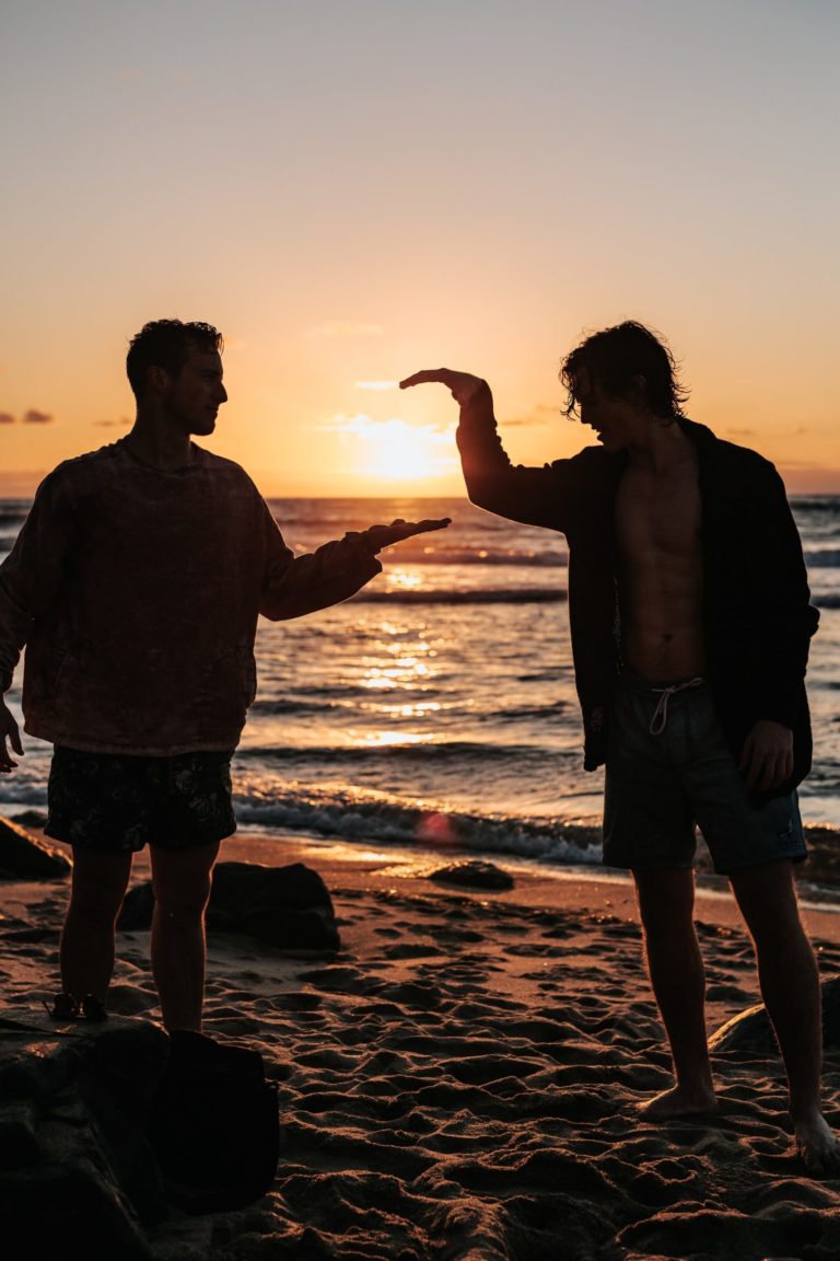 a man and a woman standing on a beach at sunset