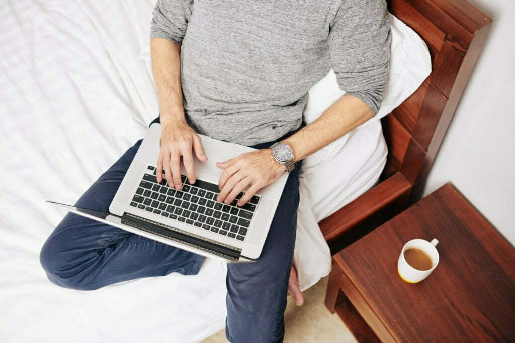 a person sitting on a bed using a laptop