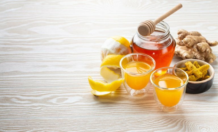 a glass of orange juice with a spoon and a glass of orange juice