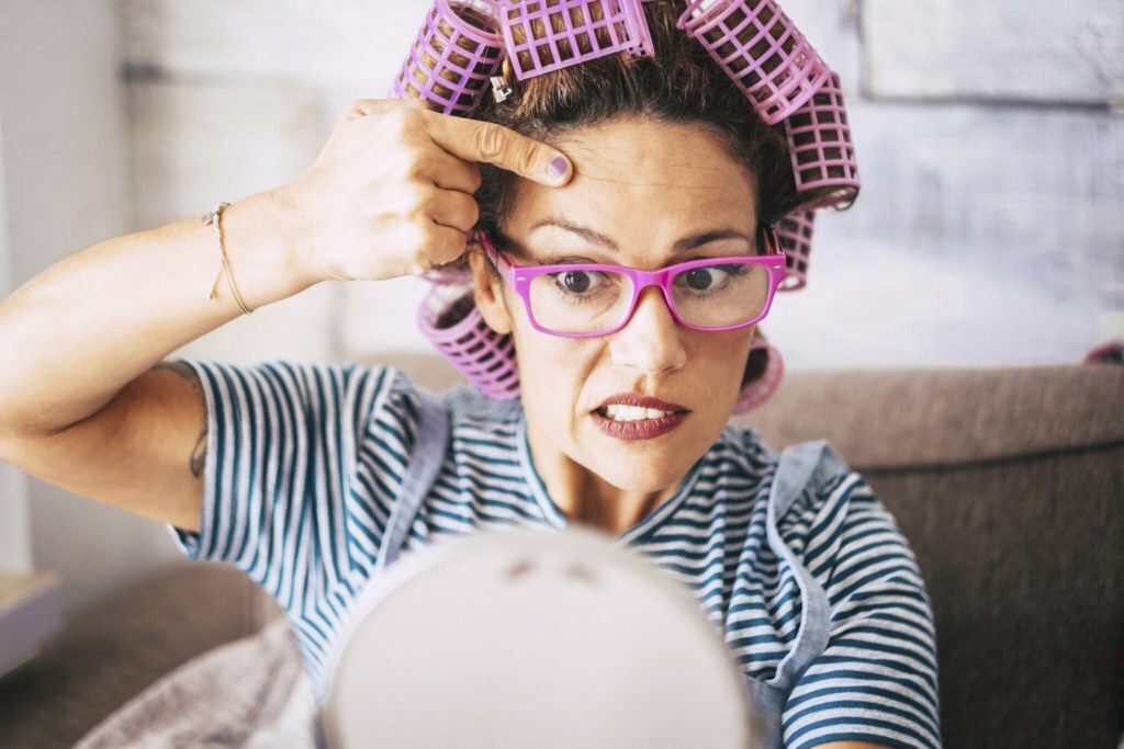 a person with glasses and a pink hat eating a piece of bread