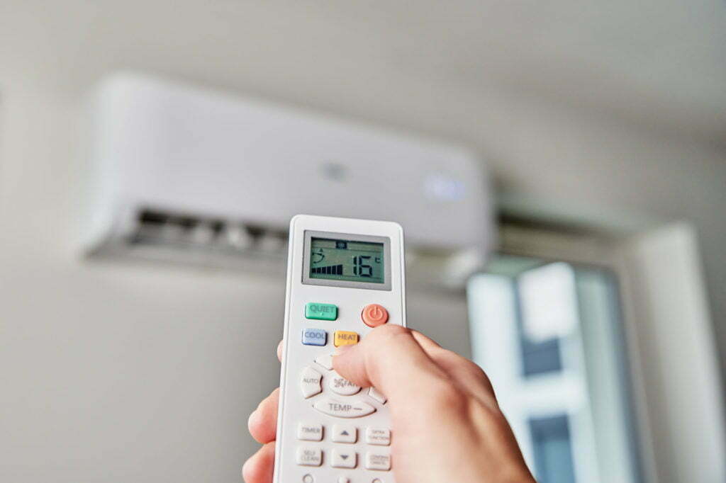 Hand adjusting temperature on air conditioner