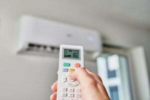 Hand adjusting temperature on air conditioner