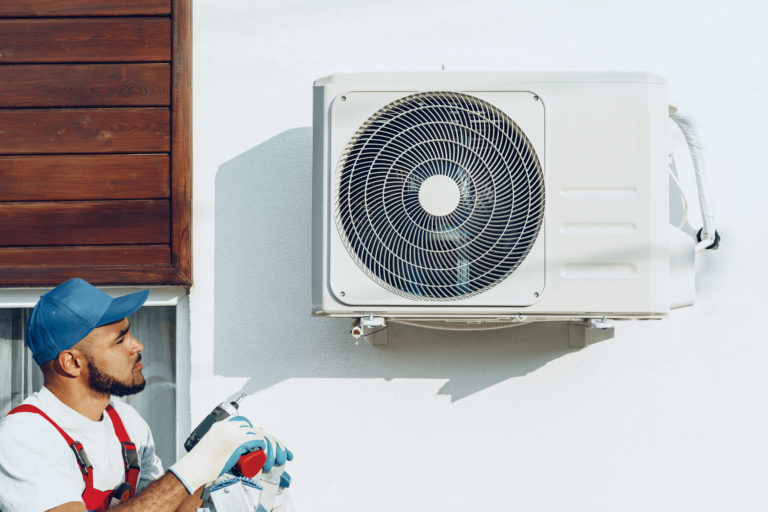 Repairman in uniform installing the outside unit of air conditioner