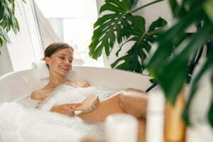 Happy young woman using brush while bathing in the tub