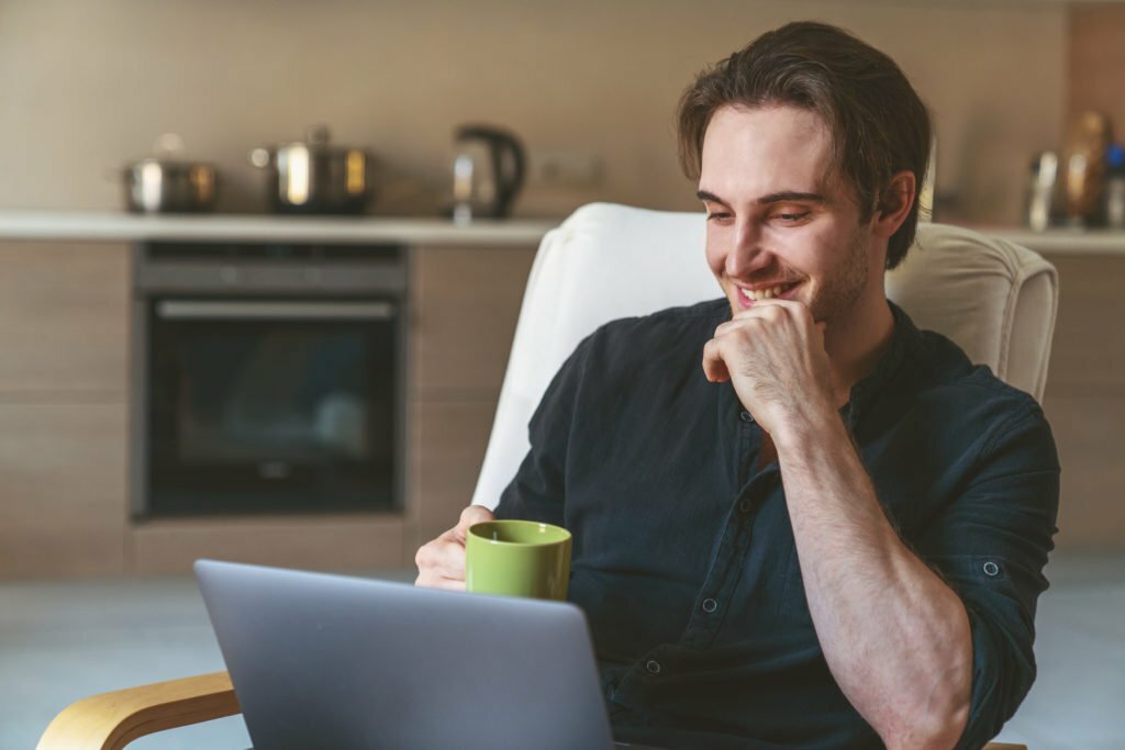 a man sitting at a table with a laptop and a cup of coffee