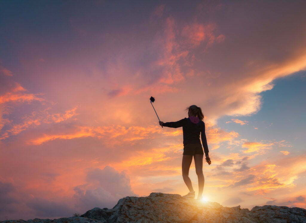 Beautiful young woman makes selfie for Instagram at sunset