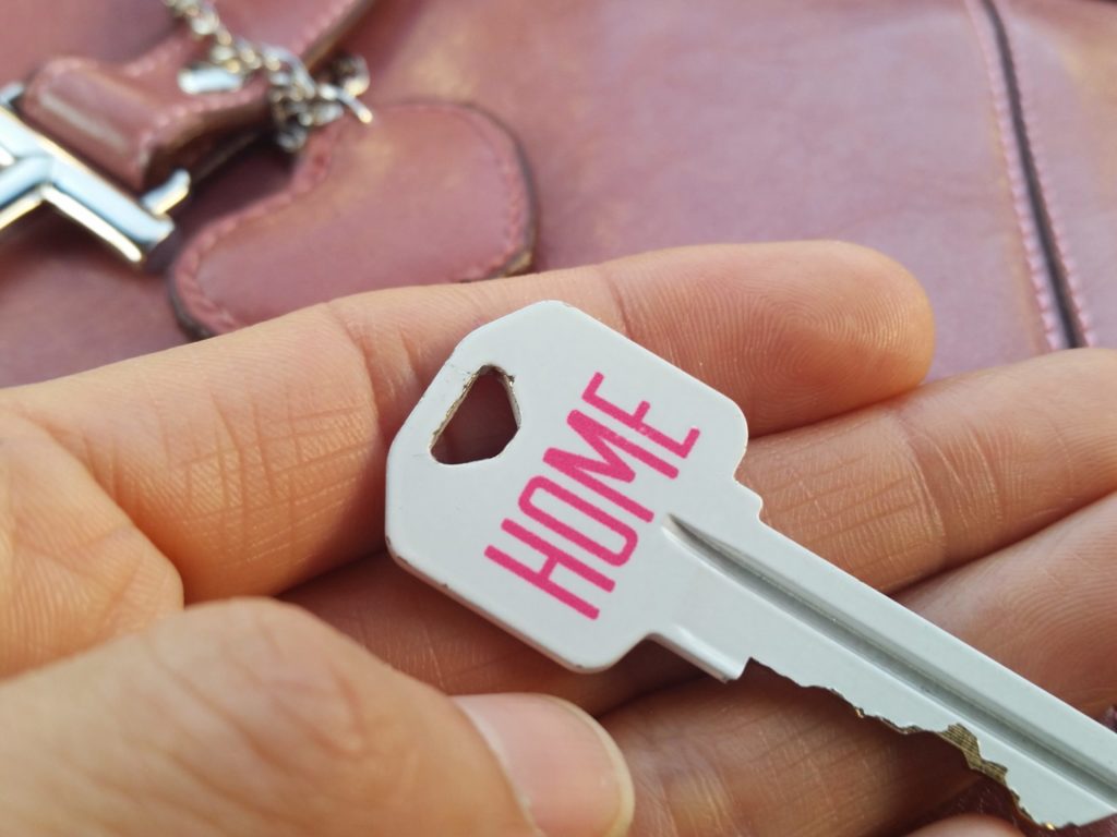Displaying the key to a new home against a pink purse