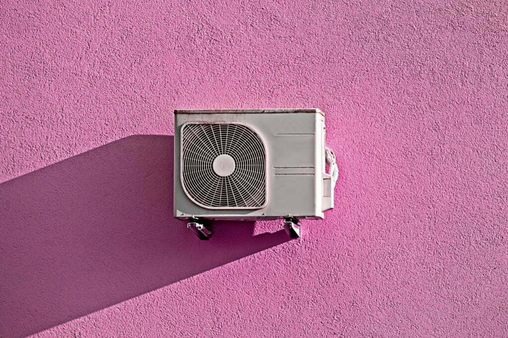Modern air conditioner compressor on grunge pink wall
