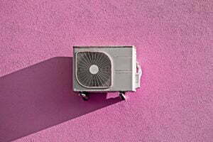 Modern air conditioner compressor on grunge pink wall