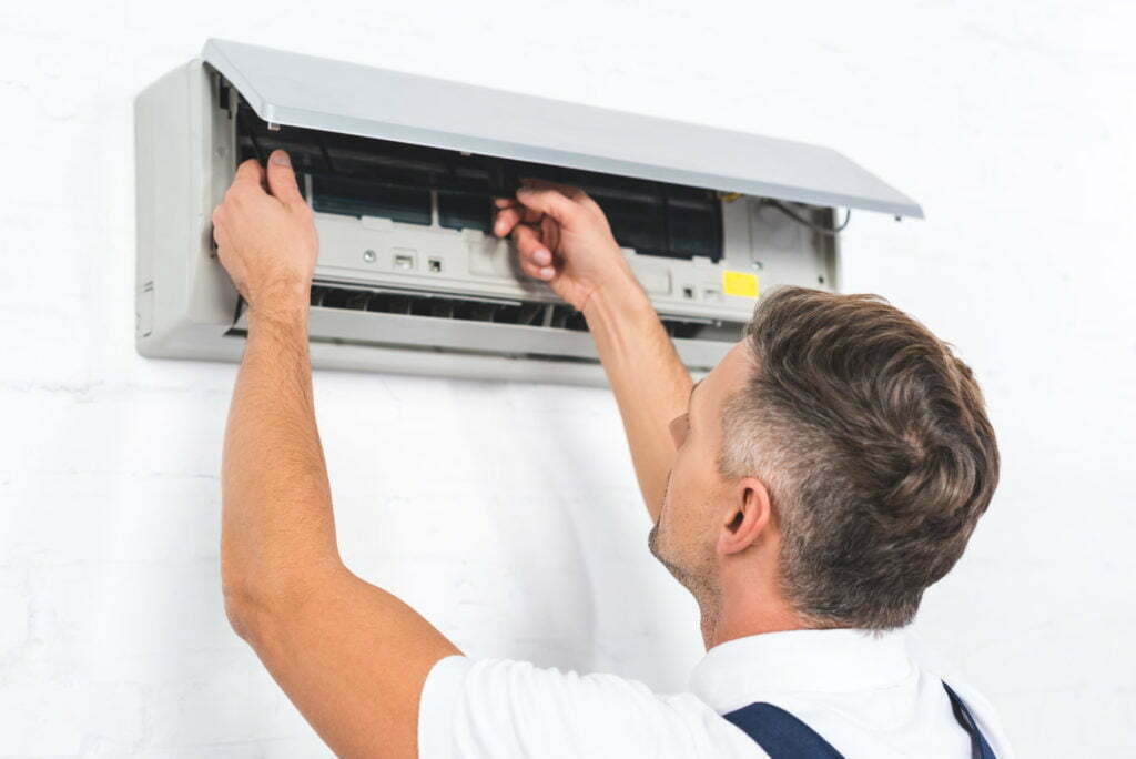 repairman fixing air conditioner on wall