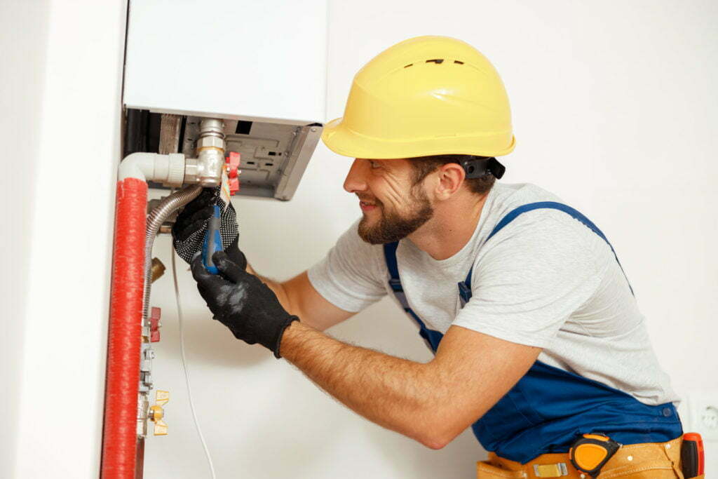 Side view of handyman, technician using screwdriver while fixing boiler or water heater, working on