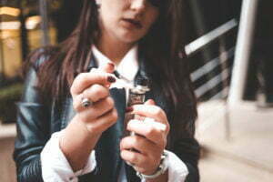 Woman refills liquid in e-cigarette closeup. Girl refills liquid in vape.