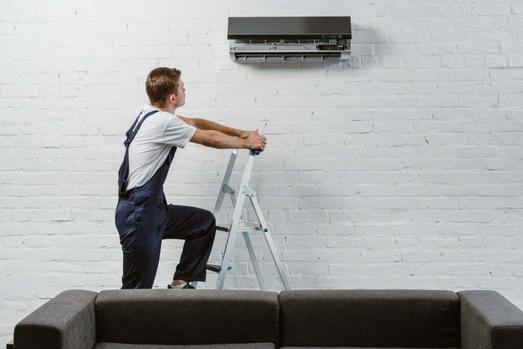 professional air conditioner repairman standing on stepladder