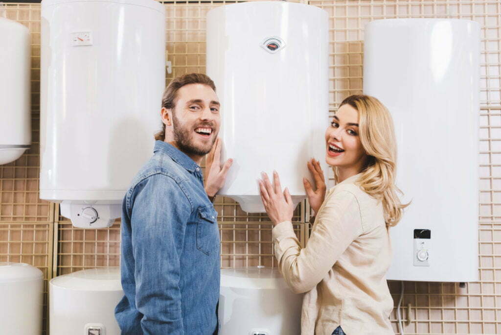 smiling boyfriend and girlfriend touching boiler in home appliance store