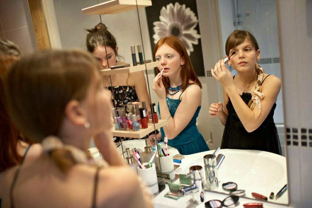 Teenage girls applying make-up