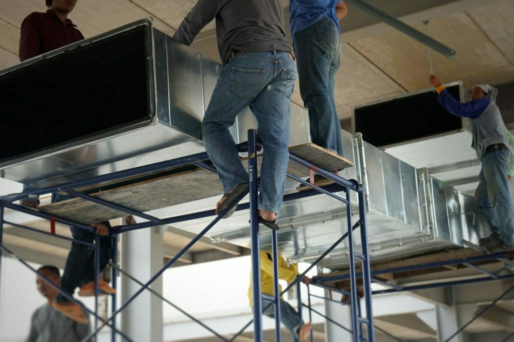 Workers are helping to raise the cool air duct of the air conditioning system to install