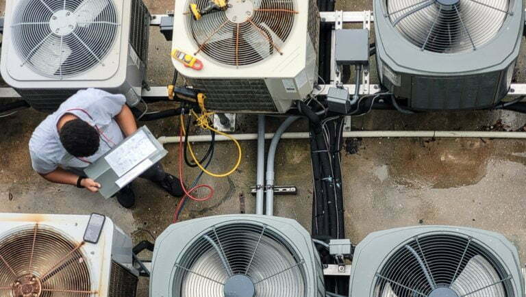 Young Latino HVAC technician doing paperwork while working on Maintenance of HVAC systems.