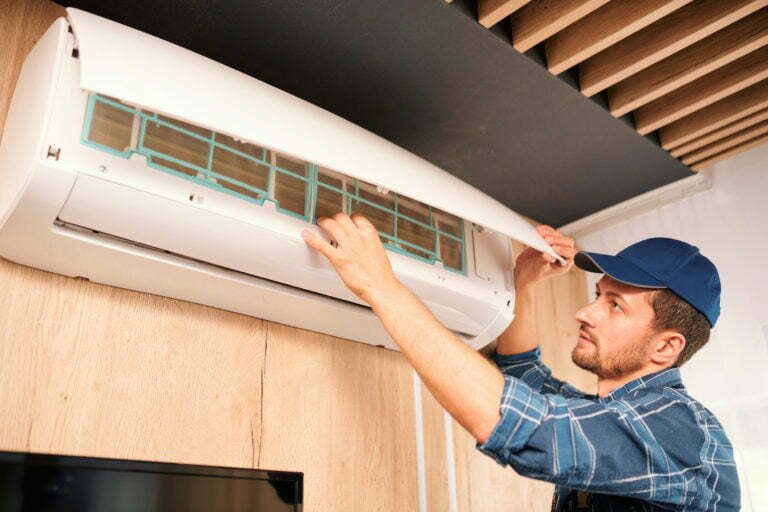 Young technician opening lid of air conditioner to check what is wrong with it