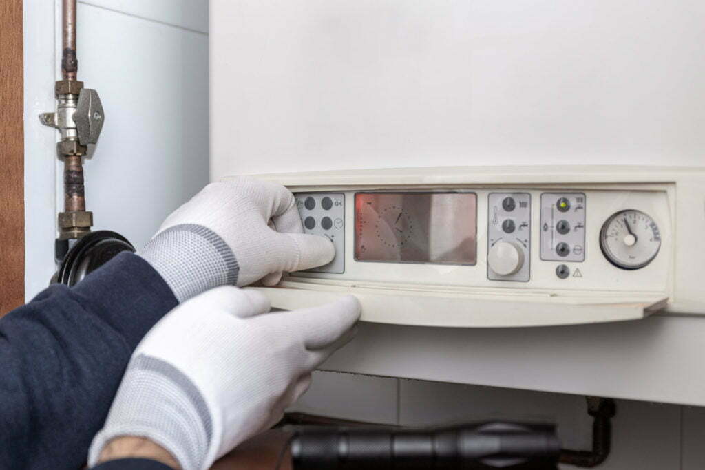 Technician servicing heating boiler in a house