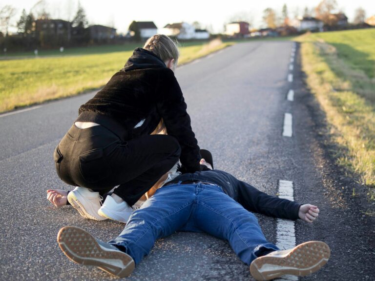 a man kneeling on the side of a road with a person kneeling on the ground